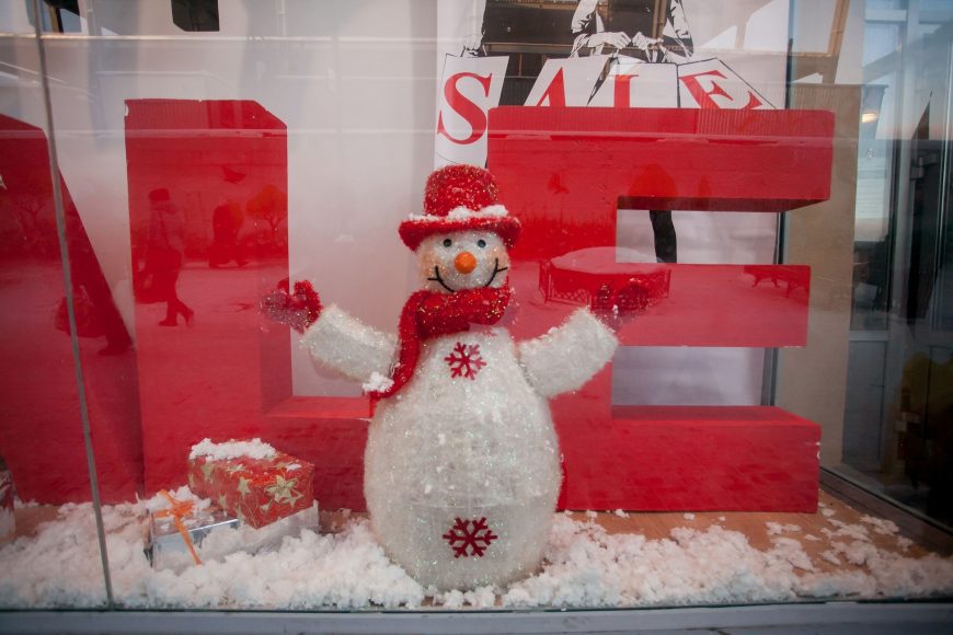 a store window with a snowman, red presents, and a SALE sign