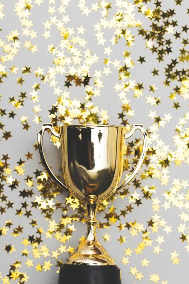a gold trophy surrounded by golden star confetti 