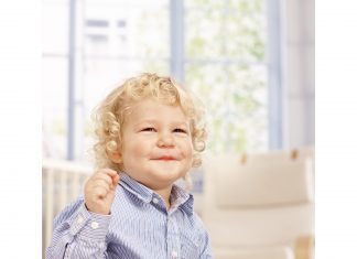 toddlerhood: a boy with blonde curly hair playing with blocks on the carpet