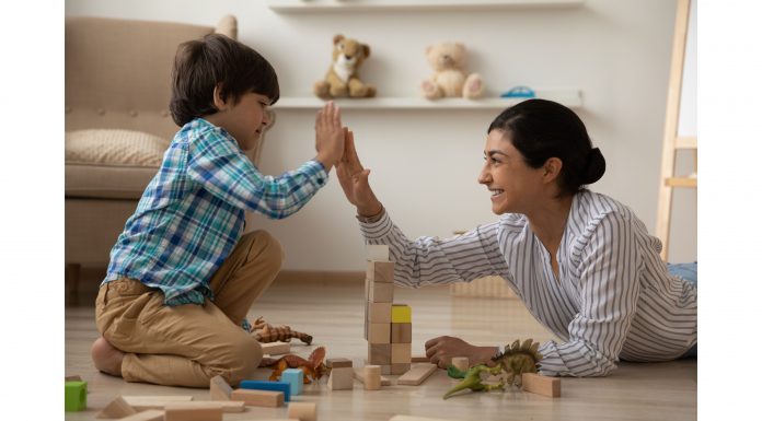 a mom and son building with blocks on the floor as they high five each other