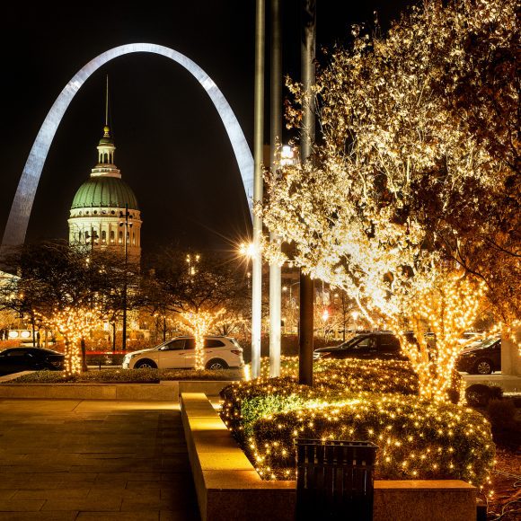 The St. Louis Arch and the courthouse near Kiener Plaza with the trees lit up with holiday lights
