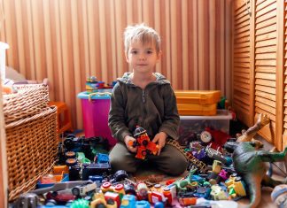 a boy sitting on the floor in his playroom, surrounded by toys