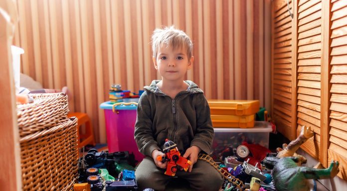 a boy sitting on the floor in his playroom, surrounded by toys