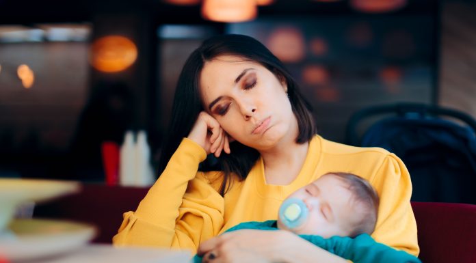 an exhausted mom holding her baby on her lap as she navigates motherhood