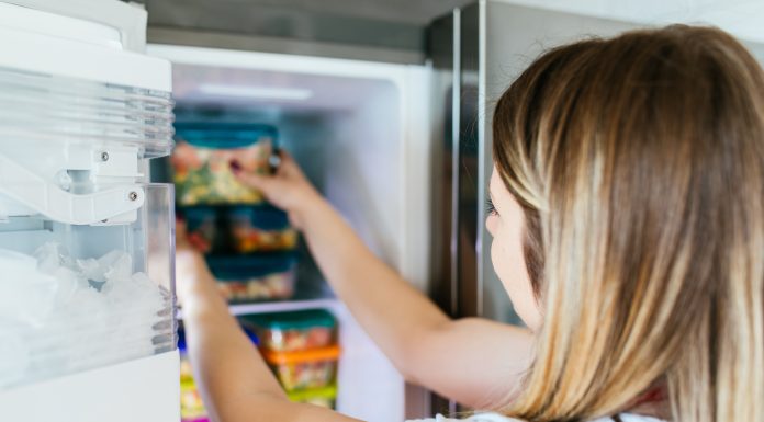 a woman reaching in the freezer for a freezer meal