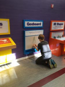 a boy playing with a Geoboard at the Magic House in St. Louis, MO