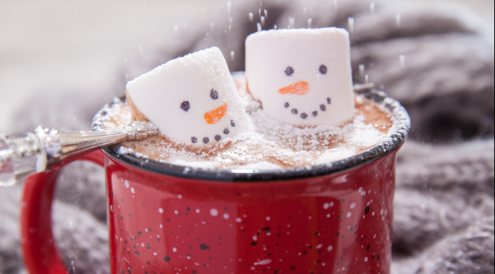 a mug of hot chocolate with snowman marshmallows and snowflake sprinkles