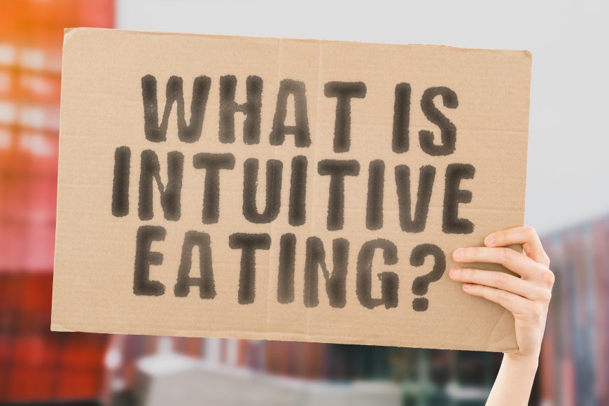 a hand holding up a sign that says, “What is intuitive eating?"