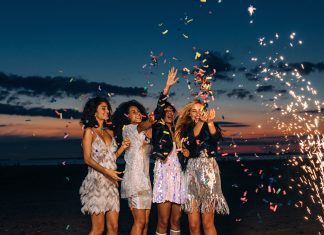 female friends celebrating outdoors with confetti and sparklers