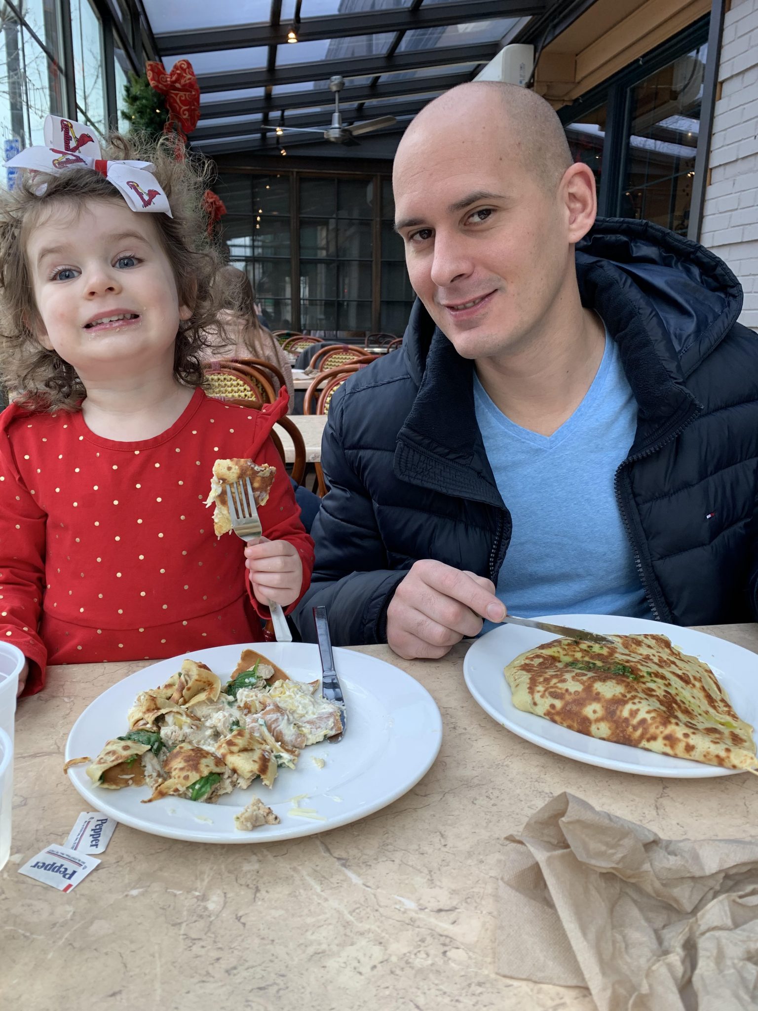 a dad and his daughter eating crepes at a local brunch spot in St. Louis