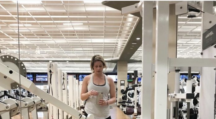 a woman standing in front of a mirror at a Lifetime Fitness gym