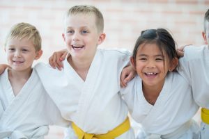 three kids, arms around each other as they wear karate his