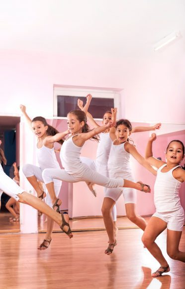 young girls leaping across the floor in dance class
