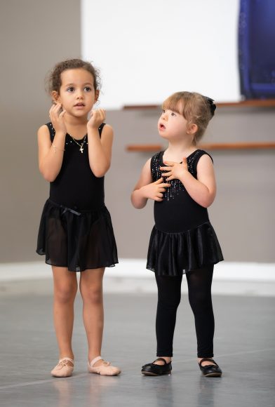 two young girls, one with downs syndrome, in black tutus in a dance class