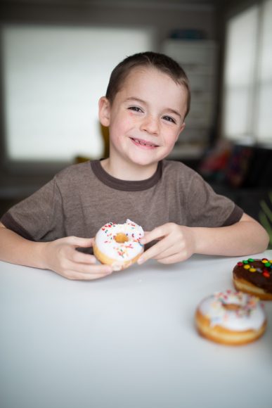a smiling boy holding a donut