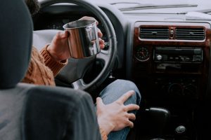 a woman sitting in the car with a cup of coffee