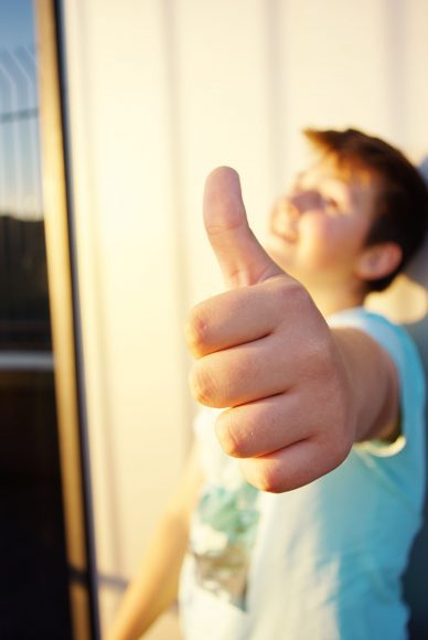 a teen boy giving a thumbs up to the camera, indicating everything is okay