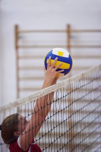 a girl reaching for a volleyball over a net