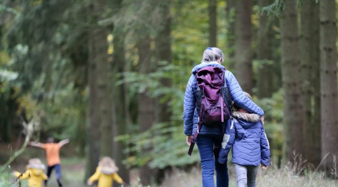 a parent and child walking on a wooded path, the moms arm around her child