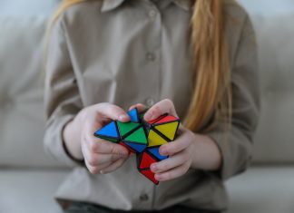 a girl on a couch working with a Rubik’s cube type fidget toy, symbolizing giftedness and perfectionism