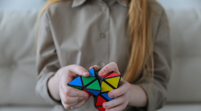 a girl on a couch working with a Rubik’s cube type fidget toy, symbolizing giftedness and perfectionism