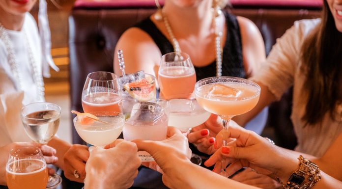 a group of women raising their glasses in cheers for moms night out