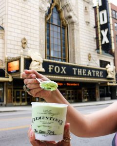 someone holding up a pint of Clementine’s Naughty and Nice Creamery ice cream in front of the Fox Theatre in St. Louis