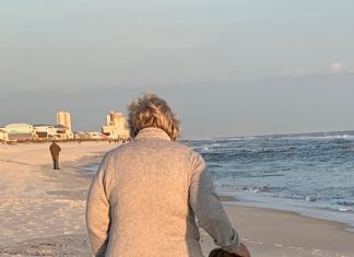a grandmother and her grandson walking across the sand at the beach