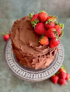 a chocolate iced cake with fresh strawberries on top