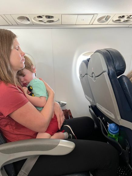 a mom on an airplane, holding her toddler son as they take the trip to Washington D.C.