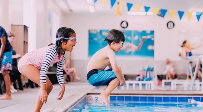 a boy and a girl jumping into a pool as they focus on swimming safely