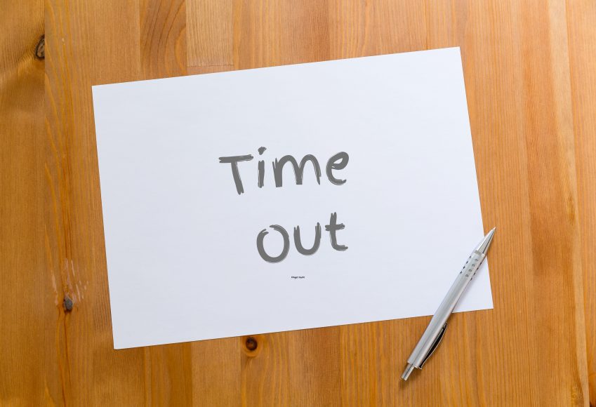 A piece of paper with a pen laying near it. The paper says, “Time Out"