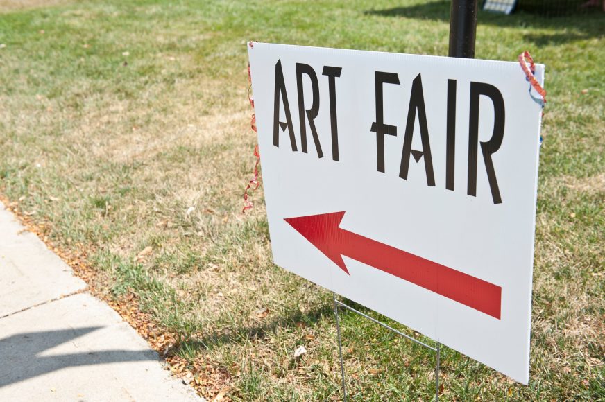 a sign that says “Art Fair” with a red arrow