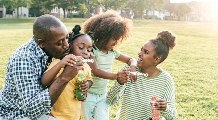 an African American family blowing bubbles in the grass