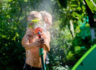 children playing with a hose in the backyard in the summer