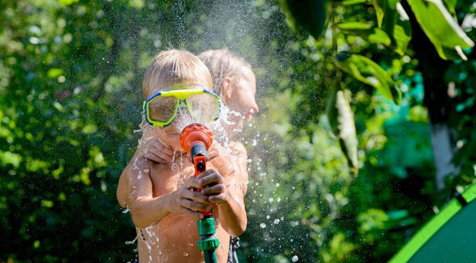 children playing with a hose in the backyard in the summer