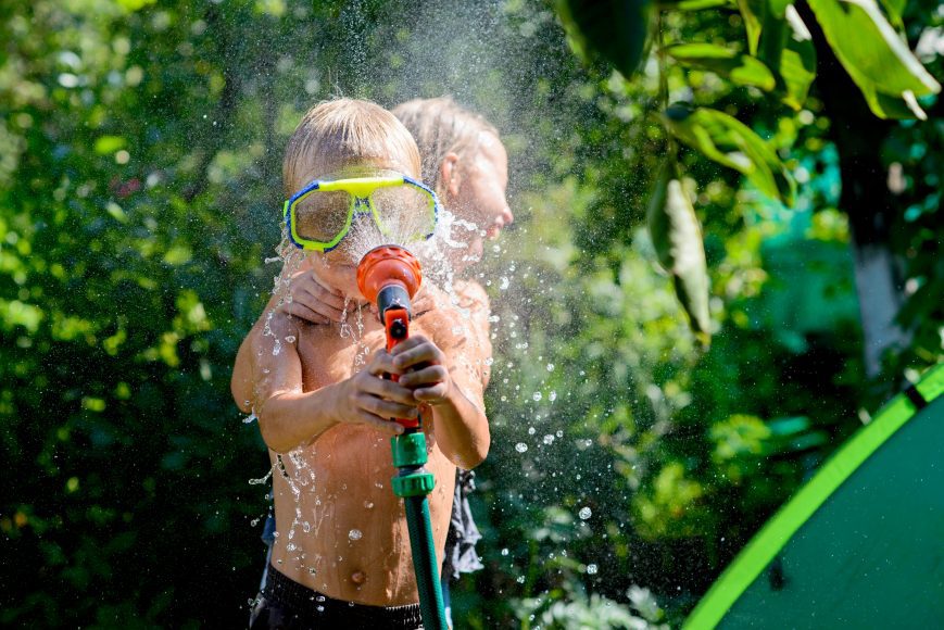 children playing with a hose in the backyard in the summer