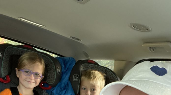 a mom in the car with two young kids in carseats as they head off on road trips