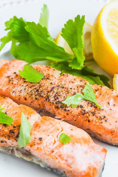 roasted salmon on a plate with lemon wedges