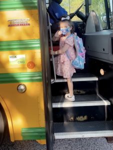 a young girl climbing on to a school bus