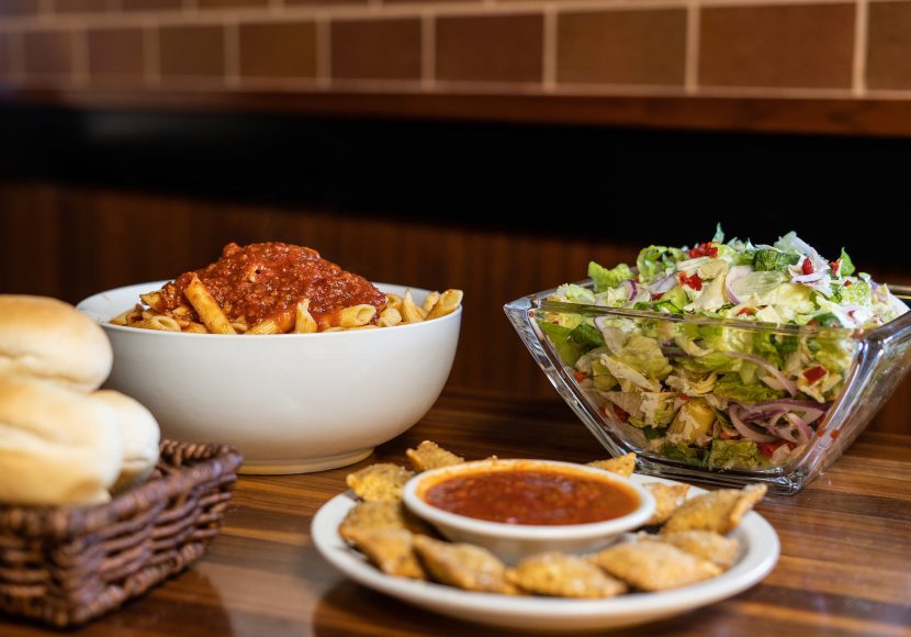 a basket of rolls, a bowl of pasta, a plate of toasted ravioli, and a bowl of salad at Pasta House in St. Louis