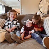 a toddler boy and girl on a couch with their new baby sister in the middle