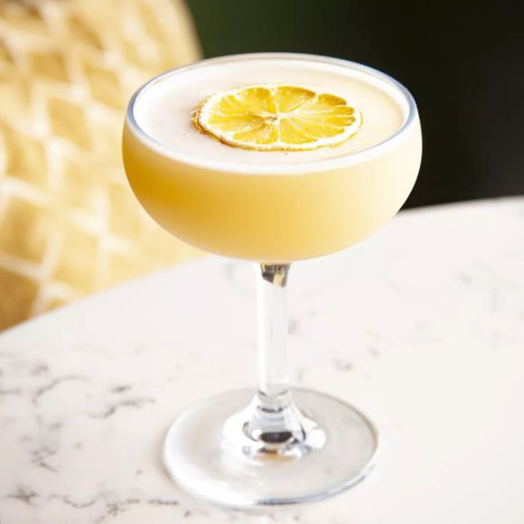 a frothy cocktail with a lemon floating on top