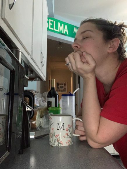 a mom leaning on the counter over a cup of coffee