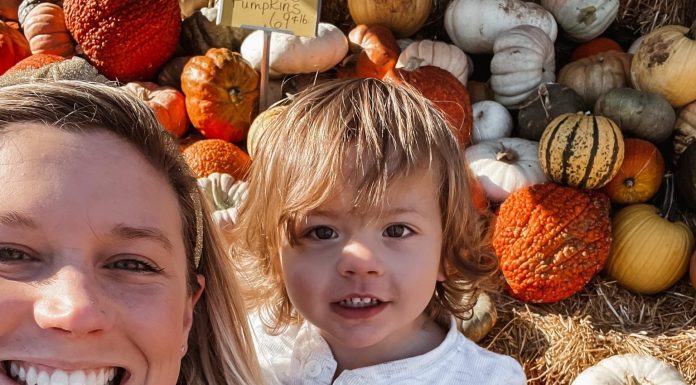 a mom holding her toddler son at a pumpkin patch