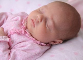 a baby dressed in pink cuddled up in sleep