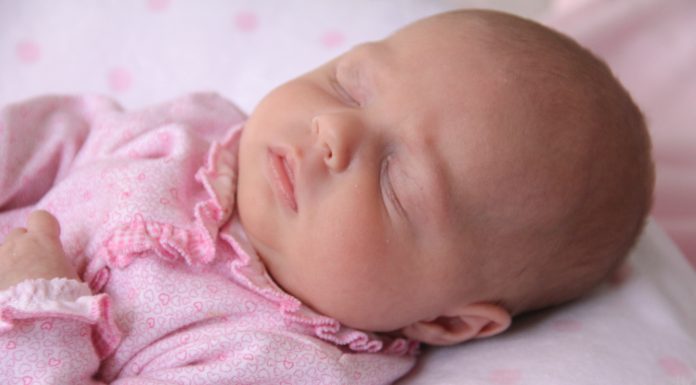 a baby dressed in pink cuddled up in sleep