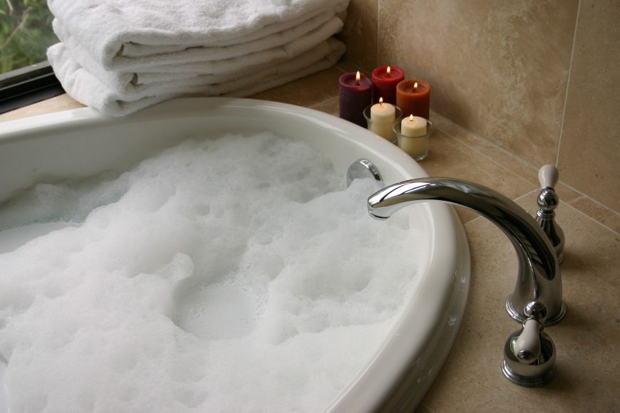 a bubble bath with candles and soft towels symbolizing self-care