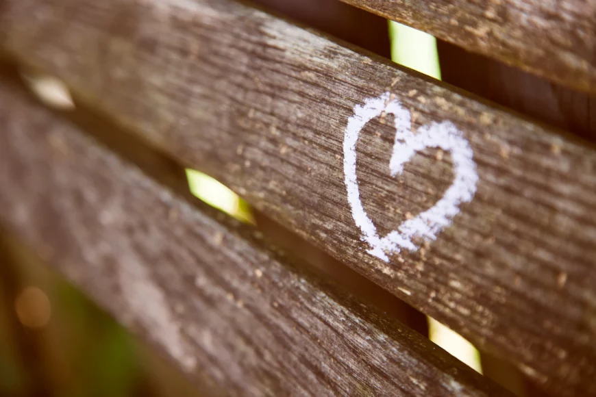 a heart drawn with chalk on a wooden fence slat