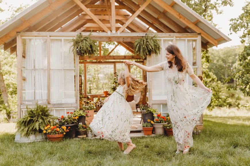 a mom twirling in the grass with her 10-year-old daughter